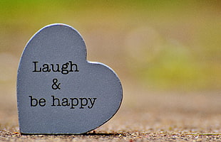 closeup photo of heart-shape gray Laugh & Be Happy deco