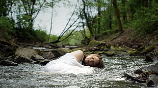 woman laying on river surrounded by trees