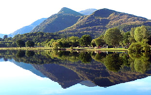 green mountain with reflection on water during day time photo