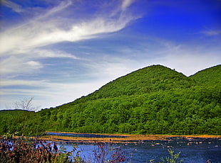 green mountains beside body of water under blue sky
