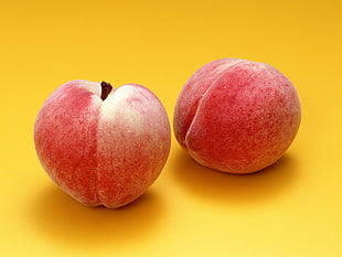 closeup photo of two Peaches on yellow surface