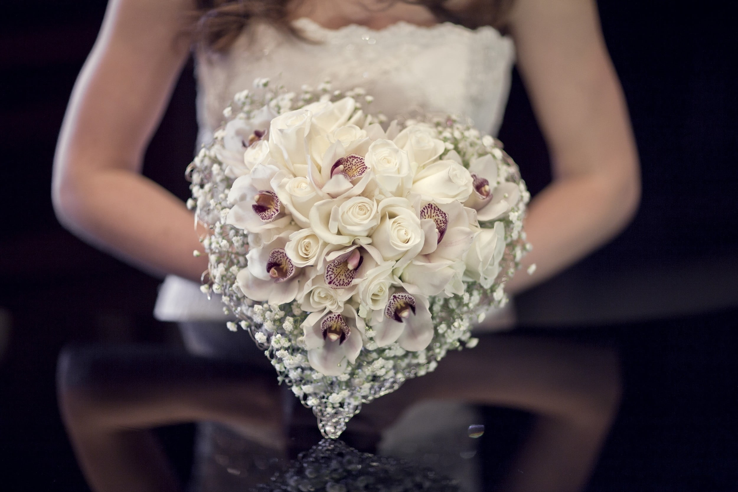 woman holding heart-shaped white and purple petaled flower arrangement