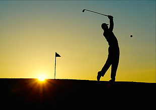 silhouette of man playing golf during sunset