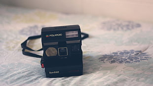 selective focus photography of Polaroid instant camera on bed comforter