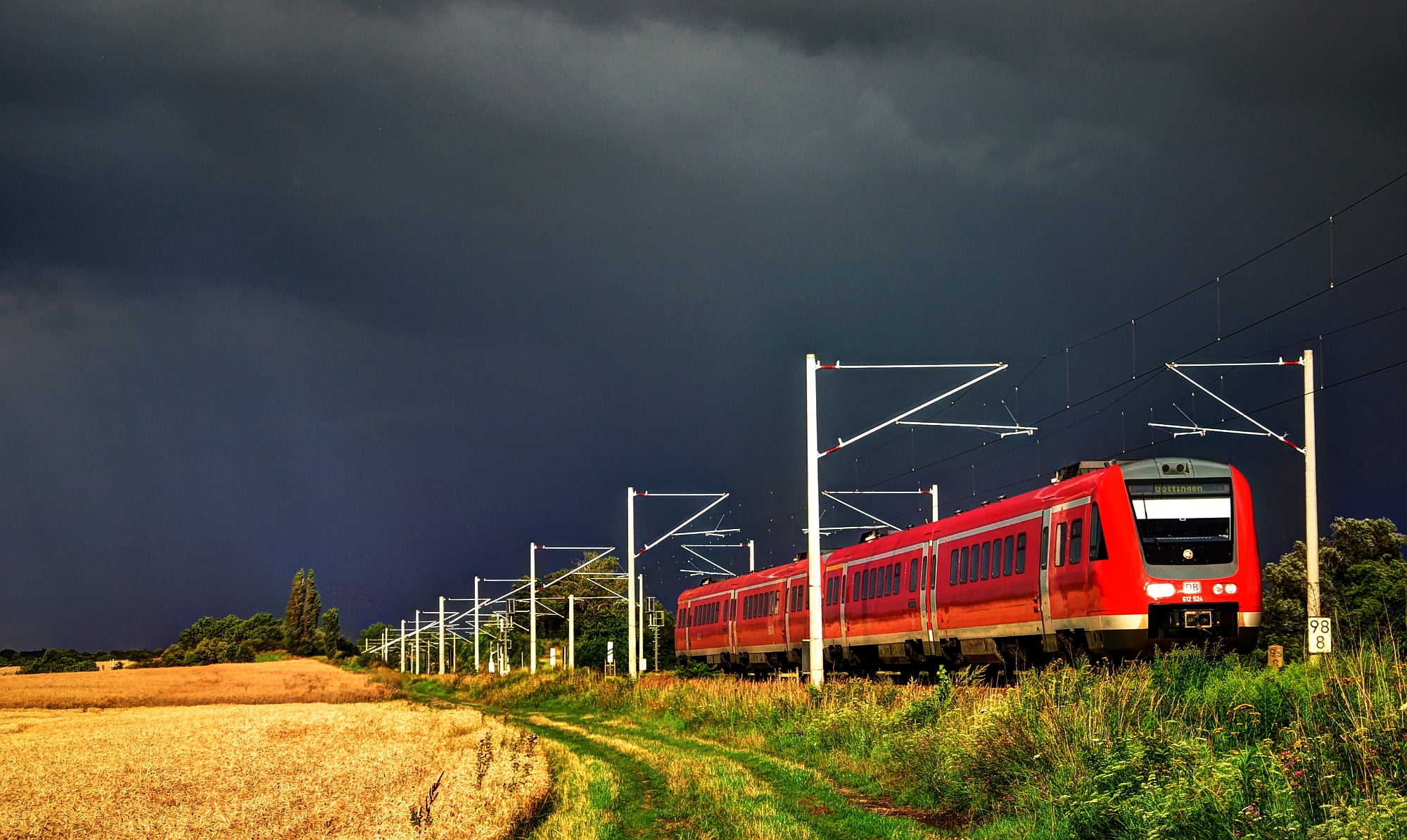 red train near wheat field with nimbustratos cloud photo