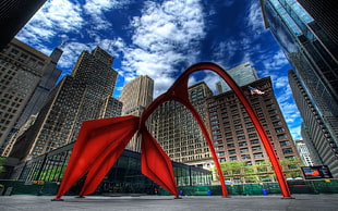 red metal statue in front of buildings