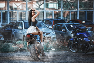 woman wearing black sleeveless top and white denim short shorts riding on blue naked bike