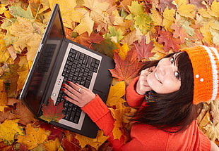 woman in red long-sleeved shirt in front of black laptop