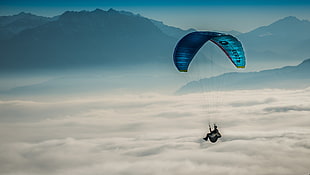 person riding a para-glider flying over the clouds