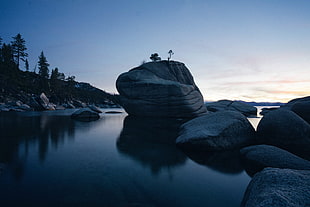 landscape photo of gray rock monolith on body of water