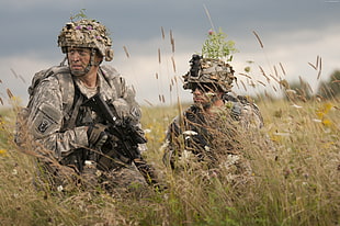 two soldier holding black assault rifle hiding at grass field