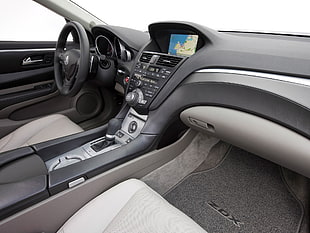 interior view of vehicle with glove compartment, car center console, and black steering wheel