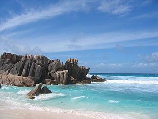 beach shore with stone cliff during day time, la digue, seychelles