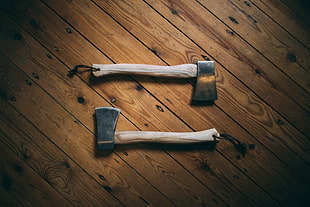 shallow focus photography of two brown axes on top of brown wooden surface