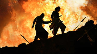 two silhouette of men near fire