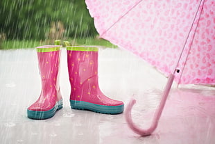pair of pink-and-blue rain boots beside pinkumbrella