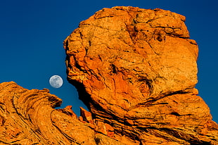 brown stone formation with moon in the background