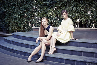 two women sitting on staircase with green leaf background