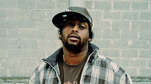 man wearing black fitted cap and white-and-grey plaid zip-up jacket