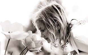 grayscale photo of a woman about to smell a flower