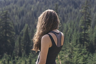 selective focus photography of woman standing with background of forest