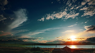 silhouette of structures near body of water on front of mountain HD wallpaper