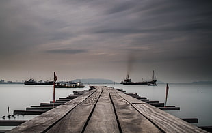 brown wooden sea dock in distant of three ships, georgetown