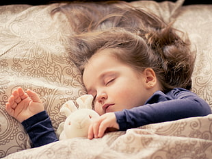 sleeping girl with rabbit plush toy in her side