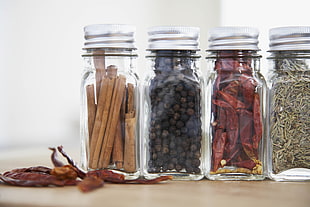four clear glass condiments jars