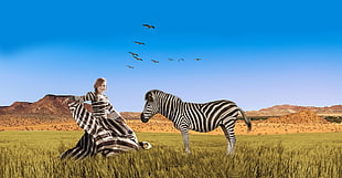 photo of woman wearing black and white zebra print dress while zebra next to her