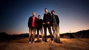 four men standing on brown soil ground near mountains