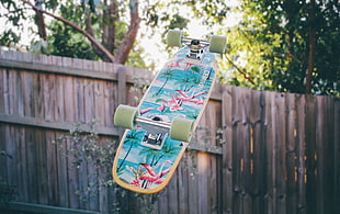 green skateboard near brown wooden fence