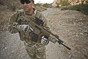 man in military suit holding assault rifle