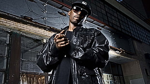 man wearing black jacket standing beside building HD wallpaper