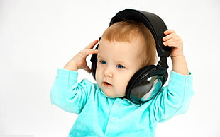 baby in teal long-sleeved shirt with black wireless headphones