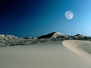 landscape photography of desert under full moon during daytime