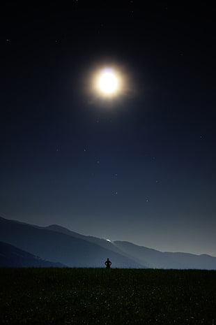silhouette of person standing on top of hill during nighttime HD wallpaper