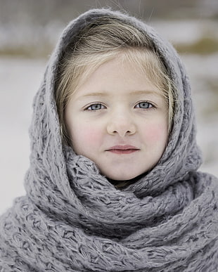 shallow focus photography of girl covered in grey knitted scarf