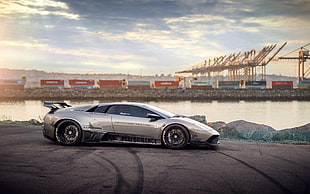silver Lamborghini sports car beside bay under clear sky during daytime