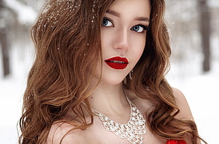 photography of woman wearing red lipstick silver-colored necklace under the snow
