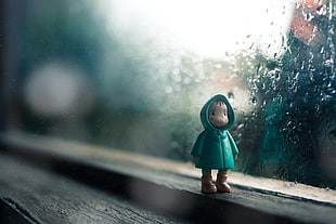 selective focus photography of plastic boy toy in green raincoat