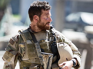 man wearing army suit holding hard helmet