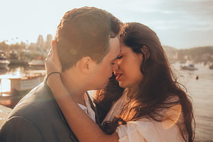 couple embracing with body of water and buildings on background