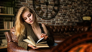woman in brown sweater holding book