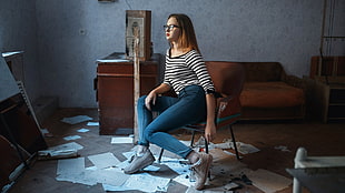 woman wearing stripe shirt and blue jeans sitting on chair in room