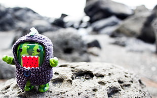 shallow focus on green domo kun figure with purple knitted sweater