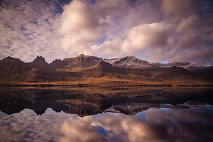 reflection photography of brown mountain near body of water