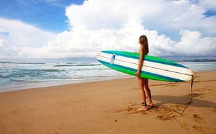 woman golding green and white surfing board near sea under blue sky during day time HD wallpaper