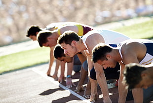 group of men leaning down on starting line during daytime