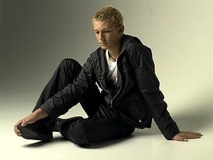Man sitting wearing black full zip jacket and pants